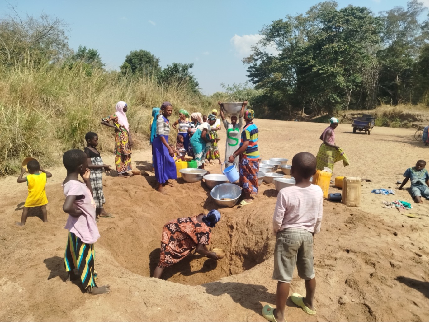 Children and women gathered at the dry sandy river bed